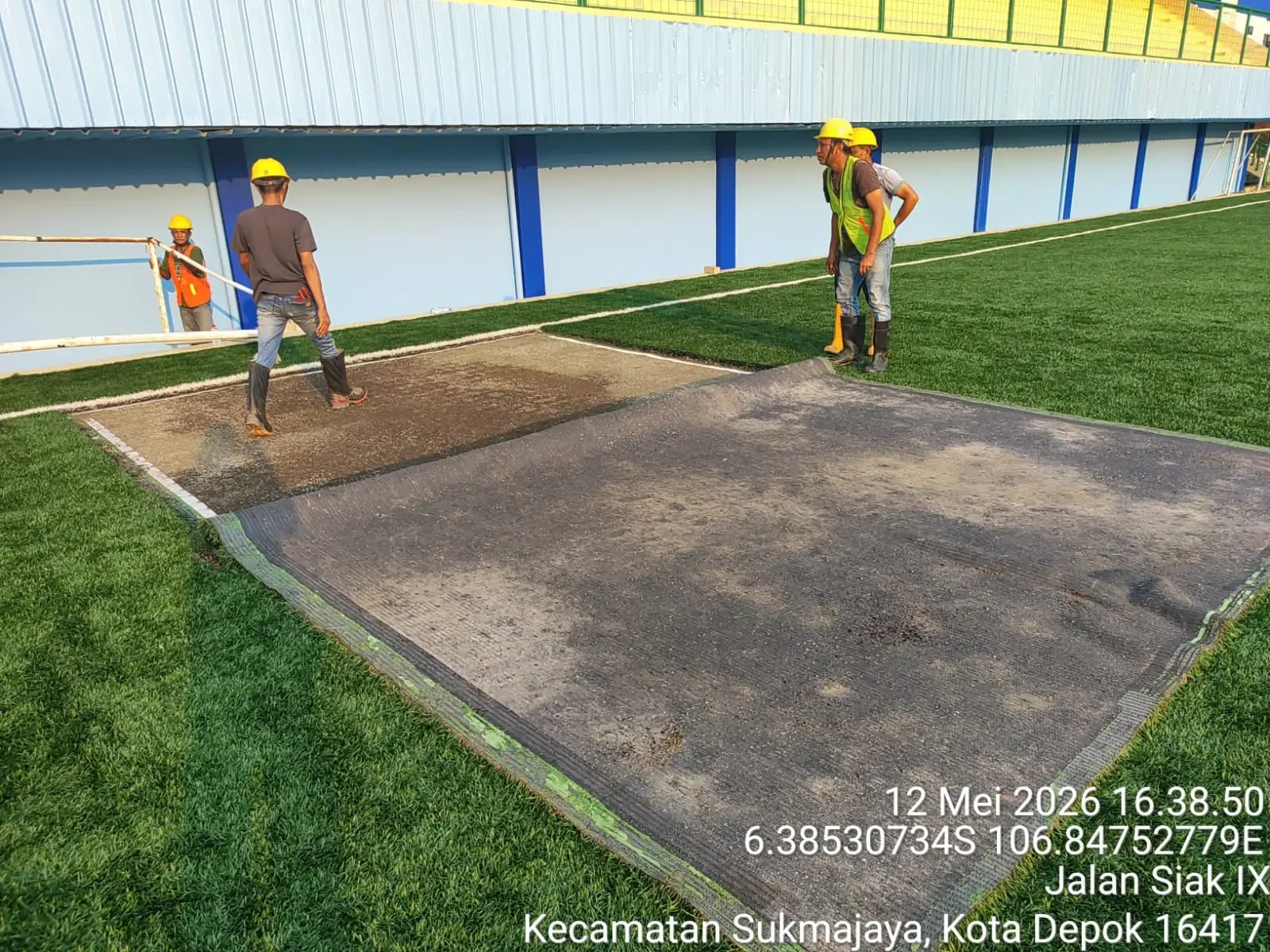 Pekerja melakukan pemeliharaan lapangan Stadion Mahakam di Kelurahan Bakti Jaya, Kecamatan Sukmajaya, Kamis (14/05/26). Pemeliharaan dilakukan untuk memperbaiki sistem drainase pada area lapangan yang kerap tergenang saat hujan deras. (Foto: dok. Narasumb