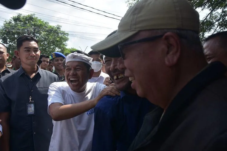 Gubernur Jawa Barat Dedi Mulyadi memijit pundak Kepala Desa Srijaya, Canih Hermansyah. (foto Kompas)