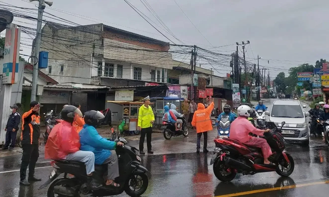 Petugas Polres Metro Depok bersama Dishub mengatur lalu lintas di kawasan Tugu Batu Sawangan, Jumat (23/05/25). (Foto: Diskominfo Depok).
