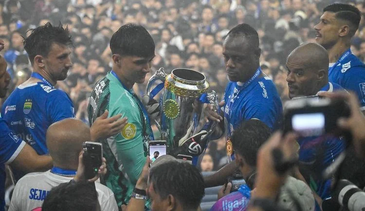 Penjaga gawang Persib bandung Kevin Ray Mendoza dan Victor Igbonefo hendak angkat piala juara Liga 1 2024-2025 di Stadion GBLA, pada Sabtu, 24 Mei 2025. (Foto Kompas)